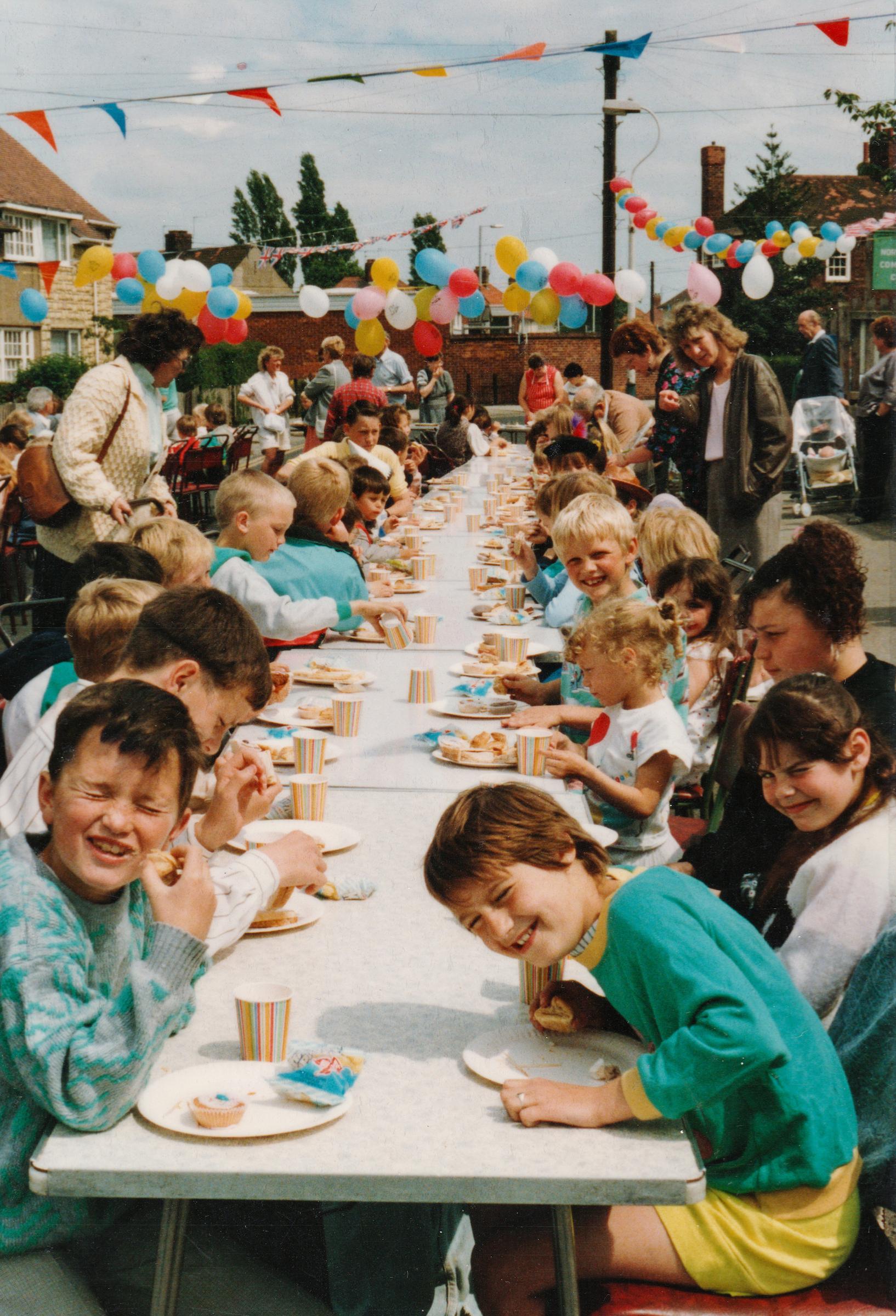 A photograph taken of a past event at North Hull community centre showing a long table with people celebrating.