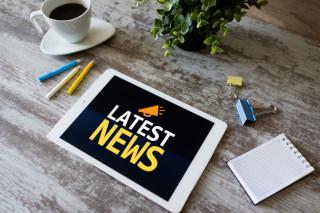 sign for latest news displayed on a table with a coffee cup and pencils.